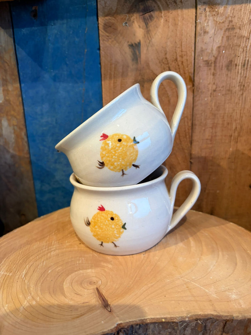 Two stacked ceramic cups with chicken illustrations on a wooden surface.